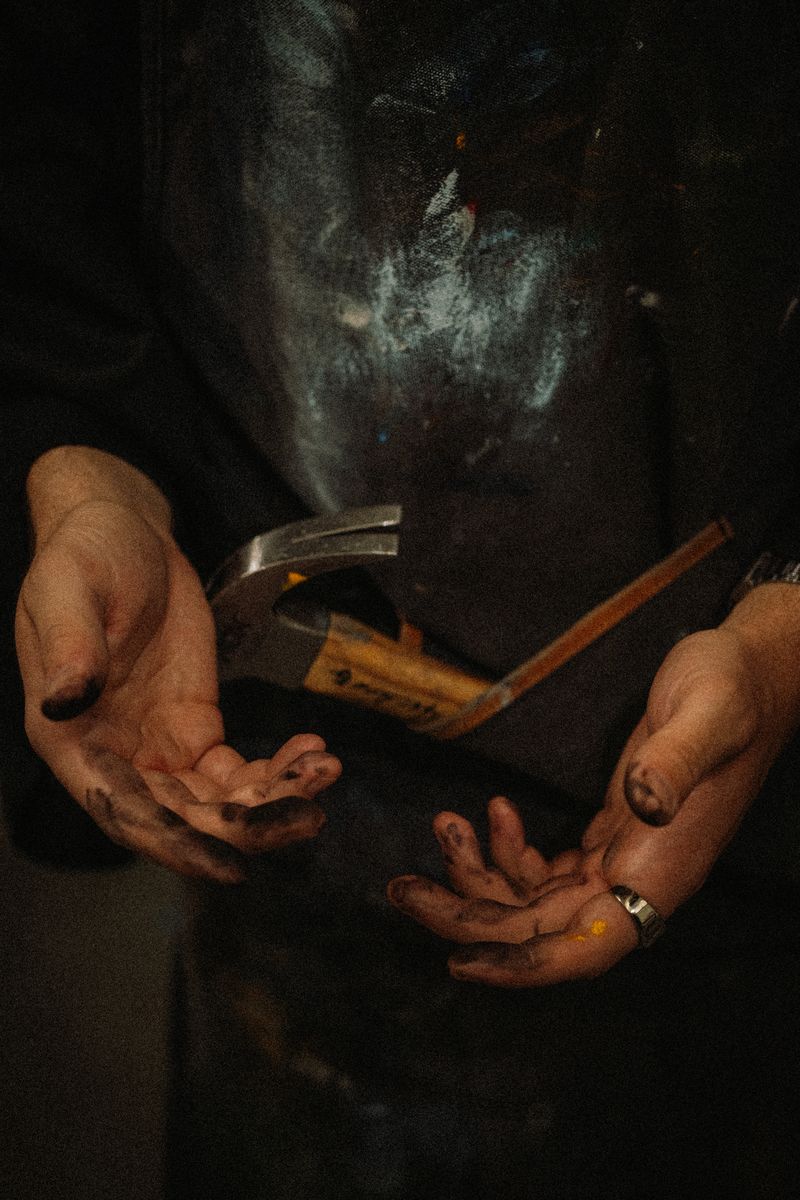 Paint-stained hands holding a hammer
