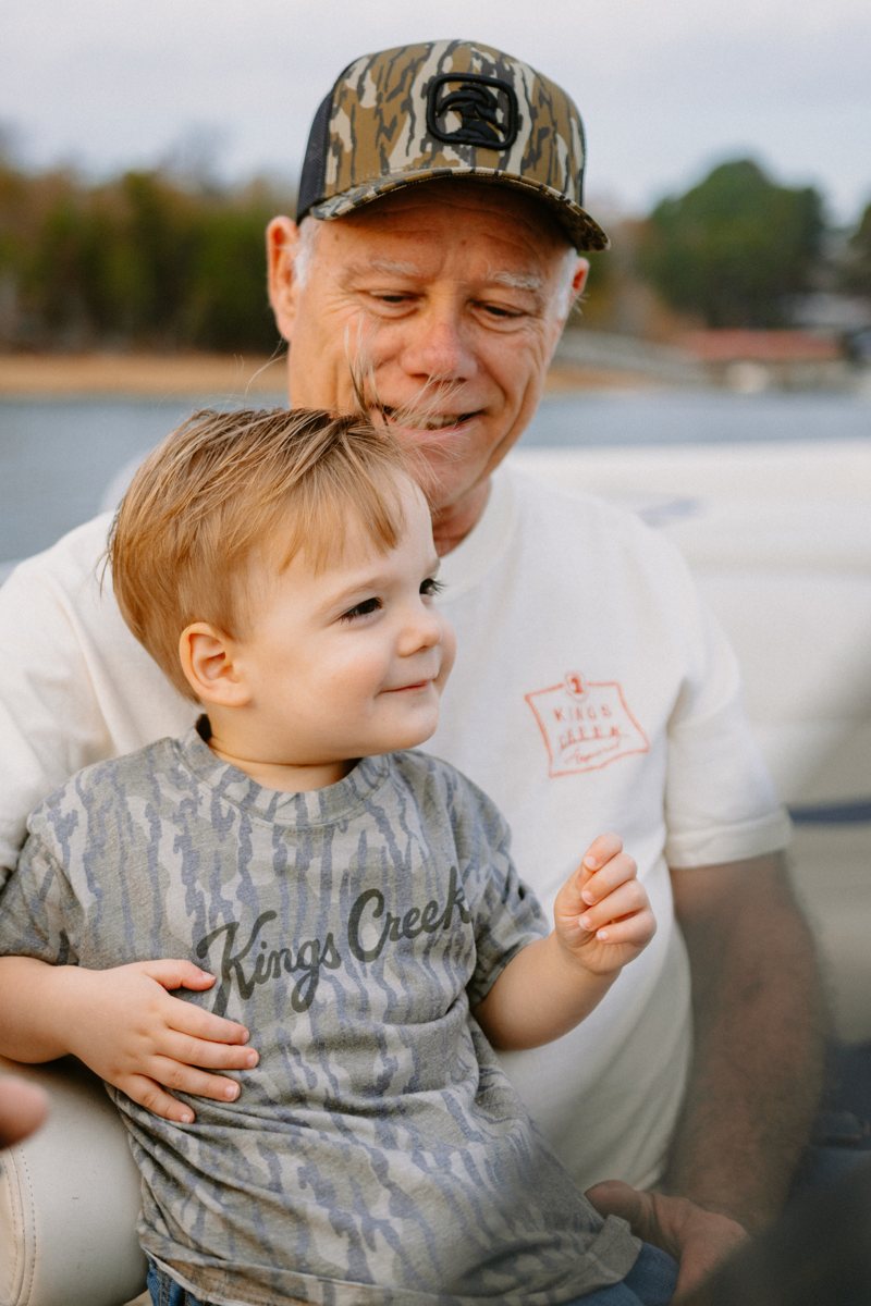 A grandfather and a toddler smiling together on a boat